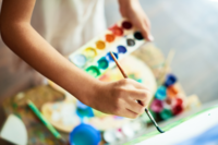 Person holding a paintbrush and watercolor palette during a creative team-building activity. This image represents artistic workshops designed to facilitate collaboration and creativity among teams. Ideal for HR professionals seeking engaging and interactive events.