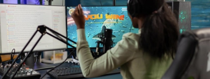 Person celebrating a win during a gaming session in a modern office setup. The scene showcases a lively virtual experience, ideal for HR professionals seeking engaging teambuilding activities that foster teamwork and communication.