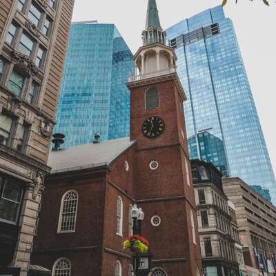 Historic church tower set against modern skyscrapers in an urban setting, ideal for team-building events that blend culture and innovation.